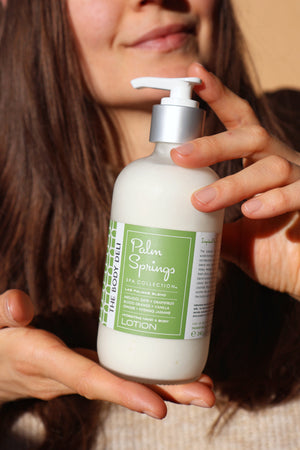 A woman holds a bottle of Lotion, emphasizing her body care routine for hydration and healthy, glowing skin.